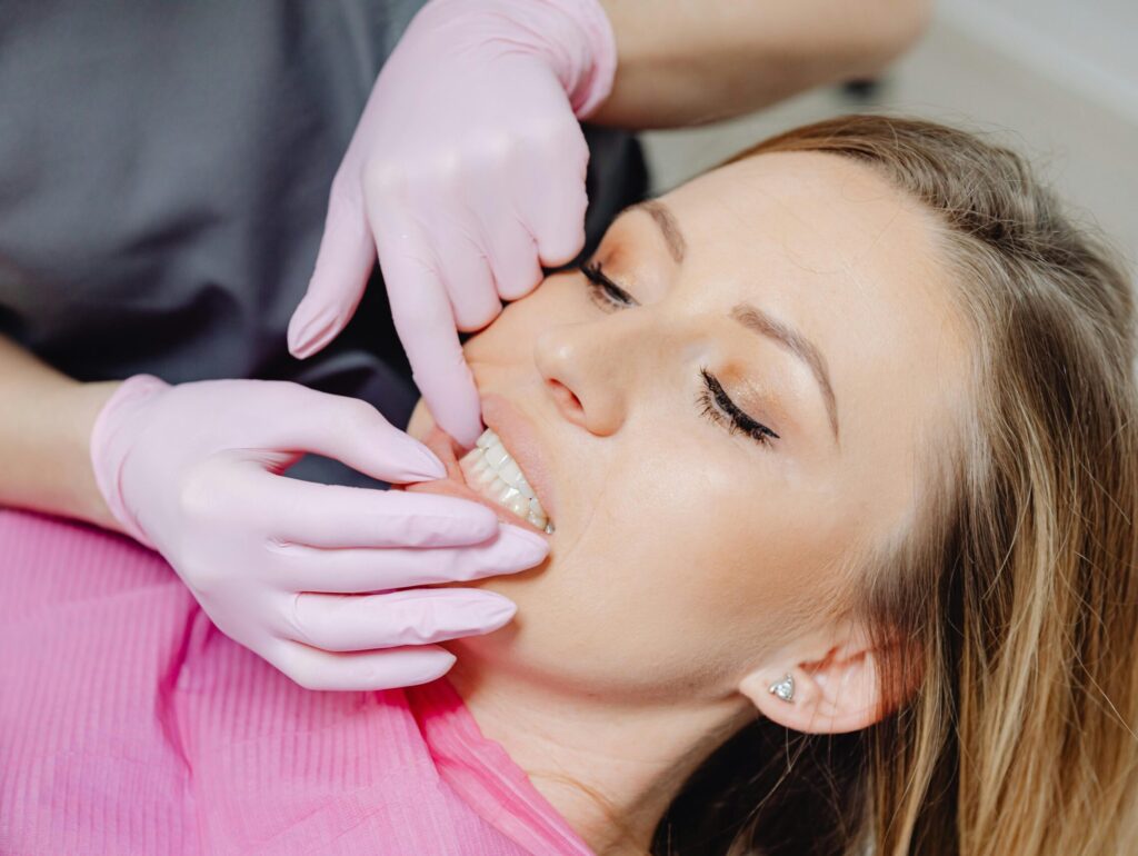 pexels-photo-6627537-6627537 A dentist wearing gloves examines a patient's teeth in a close-up view during a dental check-up.